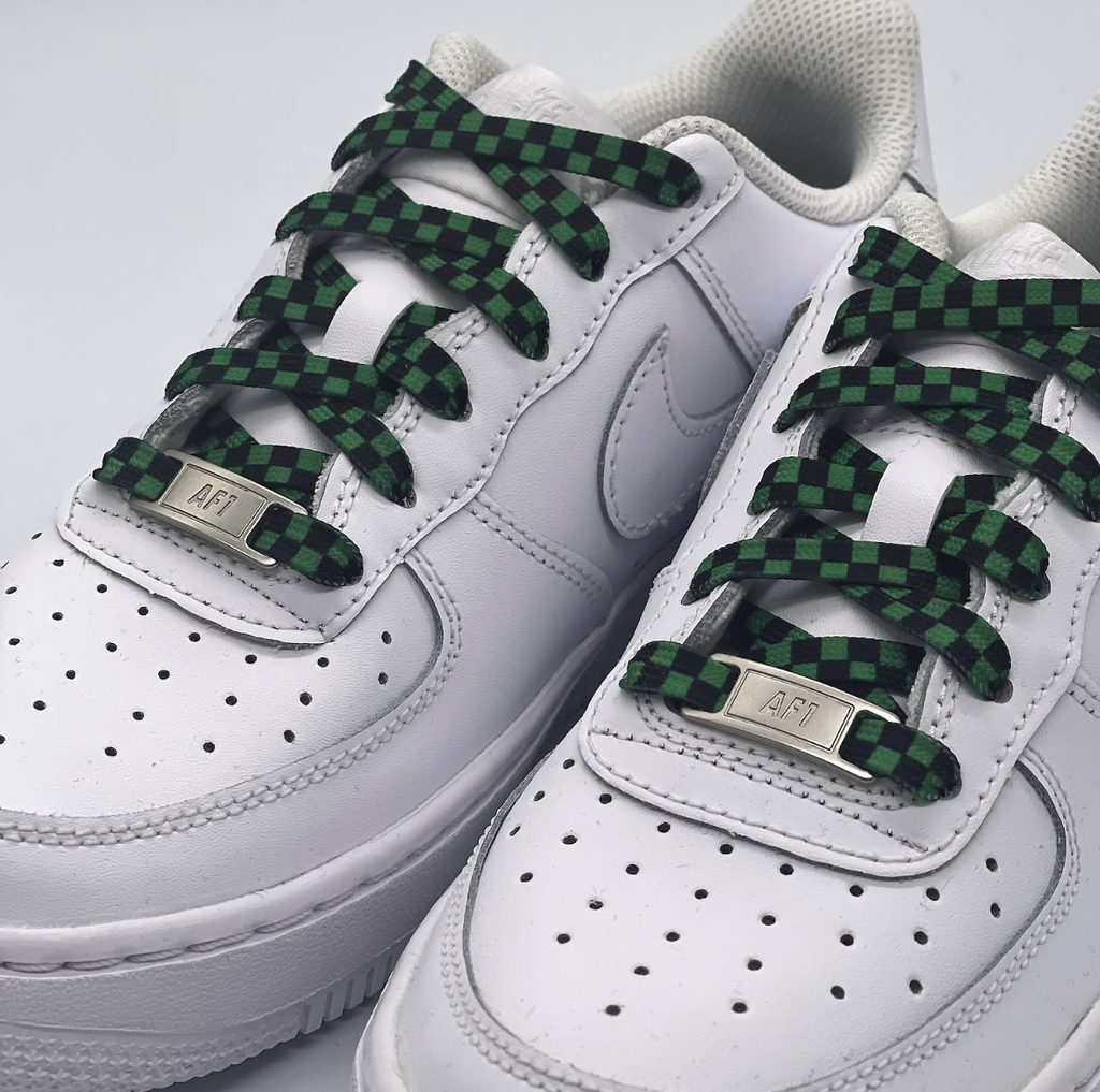 Unbearbeitetes Handyfoto weißer Nike Air Force 1 Sneaker mit grün-schwarz karierten Schnürsenkeln im Schachbrettmuster